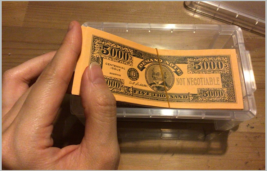 お金を100円ショップのケースにいれているところ